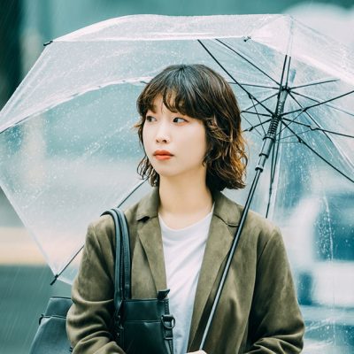 雨に日に女性が傘をさして歩いている