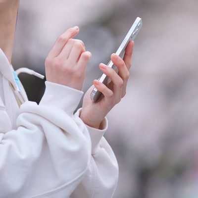 裏起毛か裏パイルか、白いパーカーを着てスマートフォンで違いを比較する女性